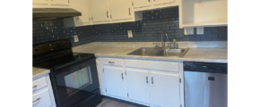 a kitchen with white cabinets and black appliances