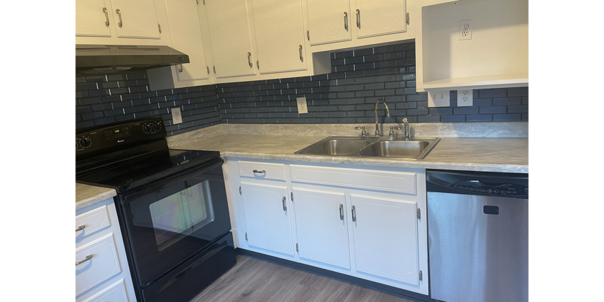 a kitchen with white cabinets and black appliances