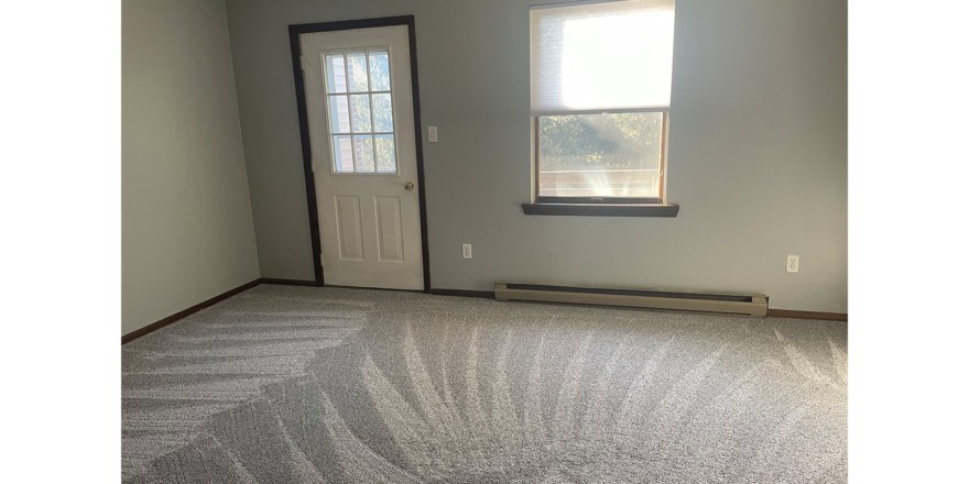 an empty bedroom with a window and a door leading to a balcony/deck