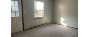 an empty bedroom with a window and a door leading to a balcony/deck