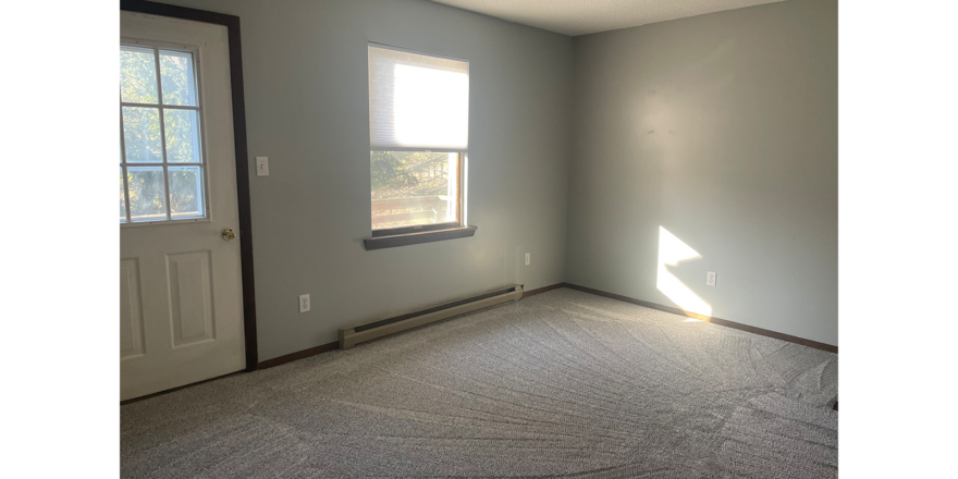an empty bedroom with a window and a door leading to a balcony/deck