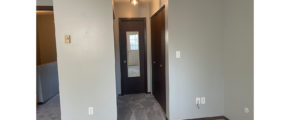 an empty room with two bi-fold closet doors, a door to the bathroom, and a carpeted floor