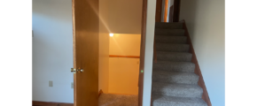 an open door leading to a hallway with stairs