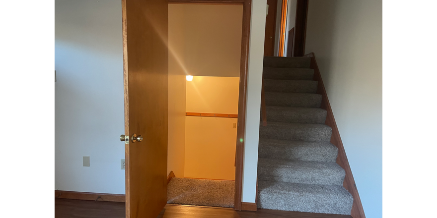 an open door leading to a hallway with stairs