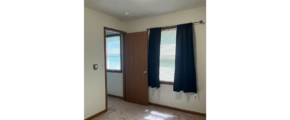 an empty room with a door, carpet, and a window