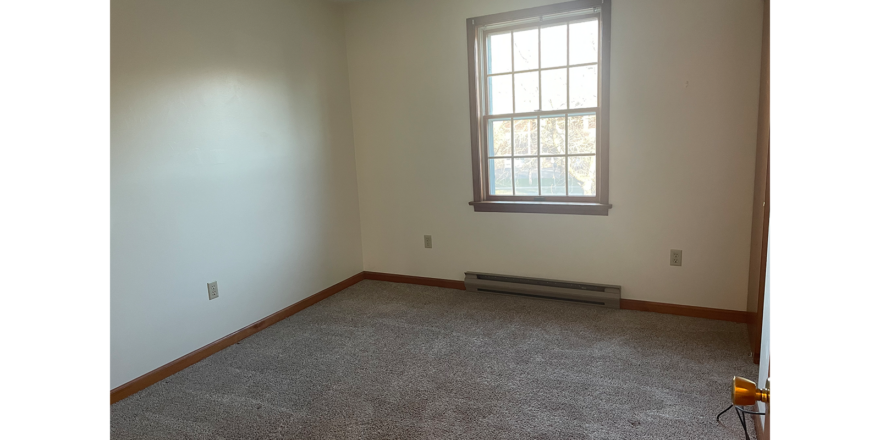 an empty room with carpet and a window