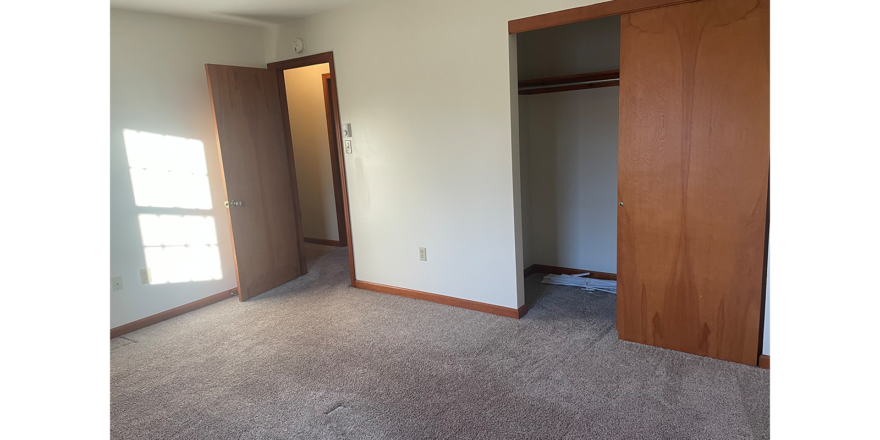 an empty room with two doors and carpet