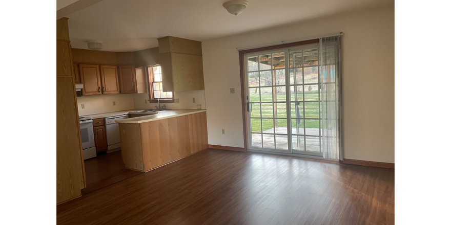 an empty kitchen and living room with wood floors