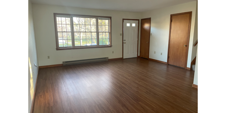 an empty living room with wood floors and windows