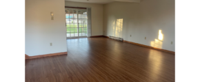 an empty living room with hard wood floors and sliding glass doors