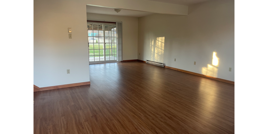 an empty living room with hard wood floors and sliding glass doors