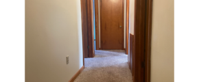 an empty hallway with a door and carpeted floor