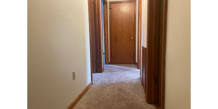 an empty hallway with a door and carpeted floor
