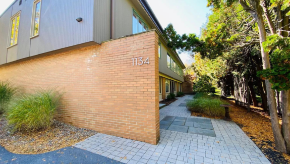 a brick and gray sided building with a walkway leading to it