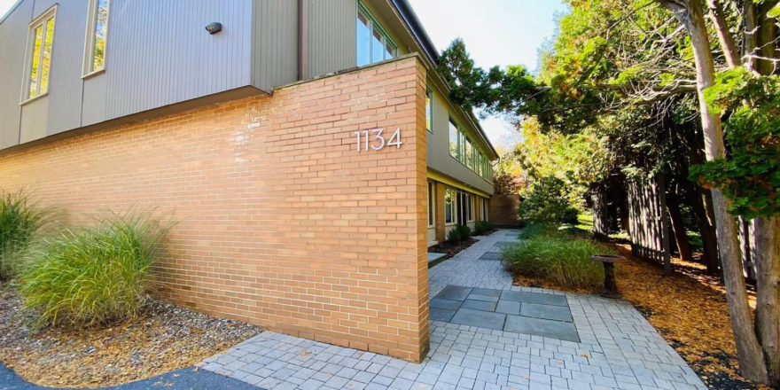 a brick and gray sided building with a walkway leading to it