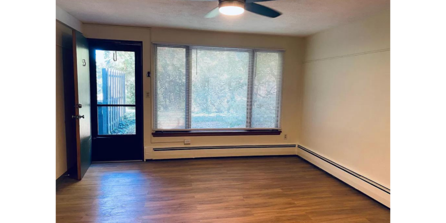 an empty room with wood floors and a ceiling fan