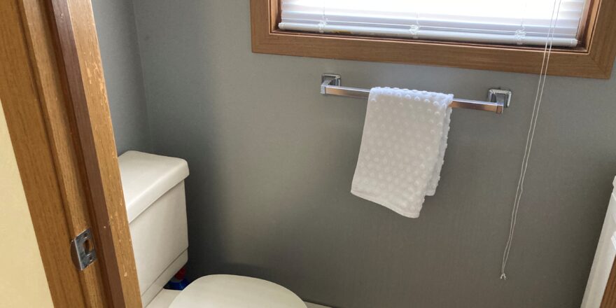 a white toilet sitting next to a window in a bathroom