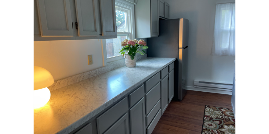 marble counters with white gray cabinets and stainless steel fridge