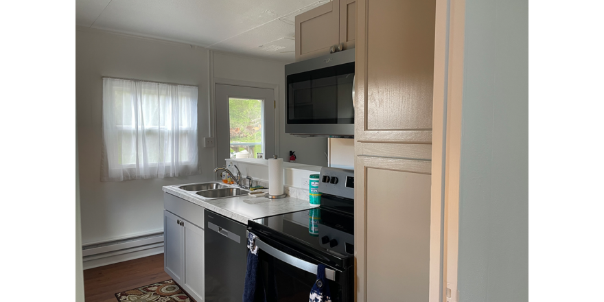 marble counter top, sink, stainless steel microwave, dishwasher, and oven, in a kitchen with brown LVP flooring