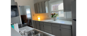 a kitchen with a sink, window, marble counter top, light gray countertops, and stainless steel appliances