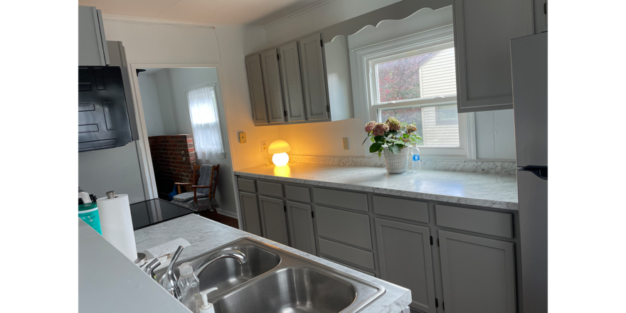 a kitchen with a sink, window, marble counter top, light gray countertops, and stainless steel appliances