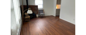 an empty living room with hard wood floors and white walls leading to kitchen