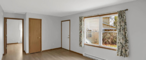 an empty room with wood floors and a window