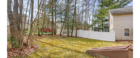 a yard with a fence and trees in the background
