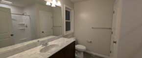 a bathroom with a toilet, sink, and mirror