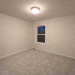 an empty room with a window and carpeted floor
