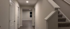 a long hallway with stairs and a clock on the wall