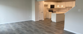 an empty living room with wood floors and white cabinets