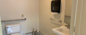 a bathroom with a toilet, sink and mirror