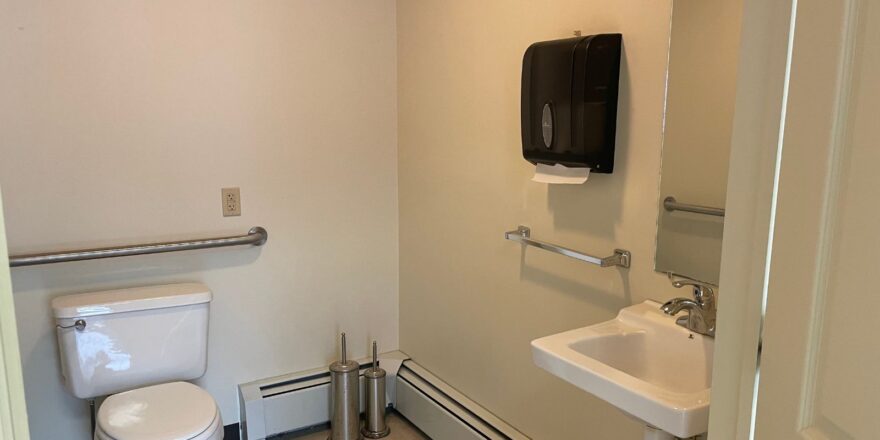 a bathroom with a toilet, sink and mirror