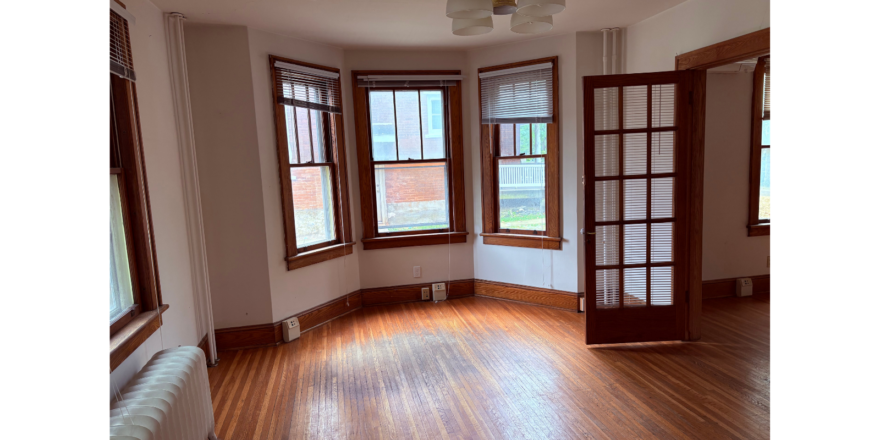 an empty room with wooden floors and three windows