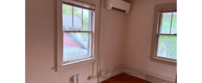 an empty room with two windows and a wood floor