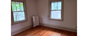 an empty room with two windows and a radiator