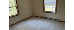 an empty room with two windows and a radiator