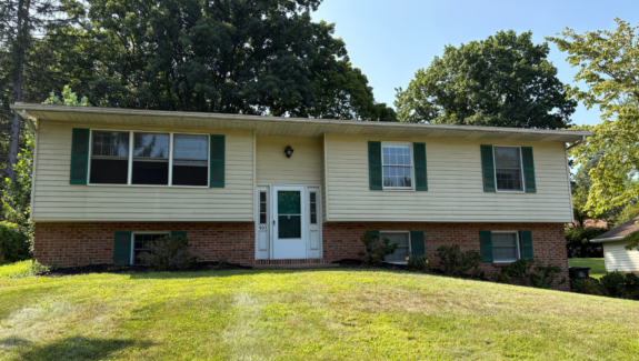 a two story house with green shutters and a white door