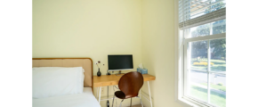 a bedroom with a bed, desk and window