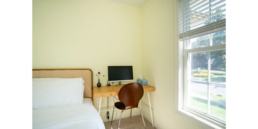 a bedroom with a bed, desk and window