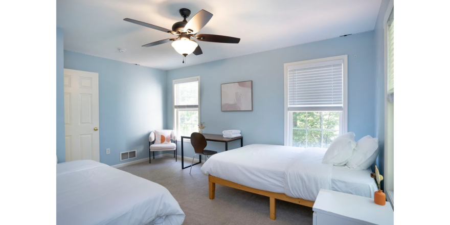 a bedroom with two beds and a ceiling fan