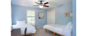 a bedroom with two beds and a ceiling fan