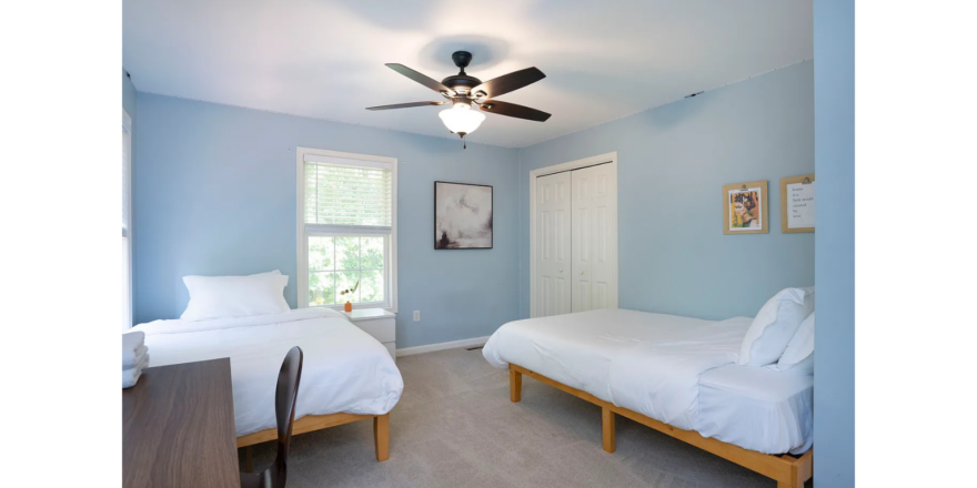a bedroom with two beds and a ceiling fan