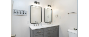 a bathroom with two sinks, a toilet and two mirrors