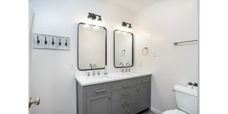 a bathroom with two sinks, a toilet and two mirrors