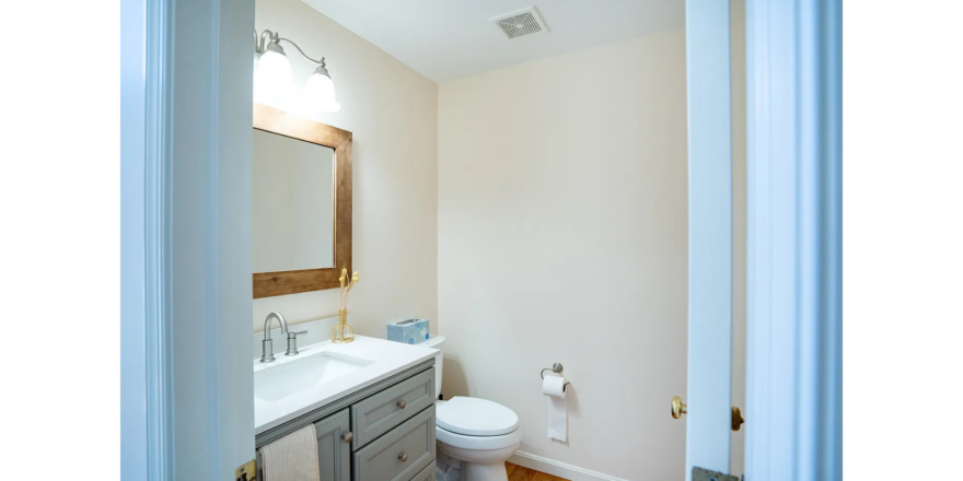 a bathroom with a toilet, sink and mirror