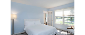 a bedroom with a white bed and two windows