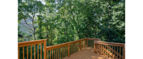 a wooden deck with railings and trees in the background