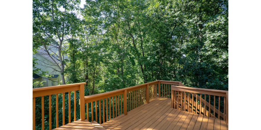 a wooden deck with railings and trees in the background